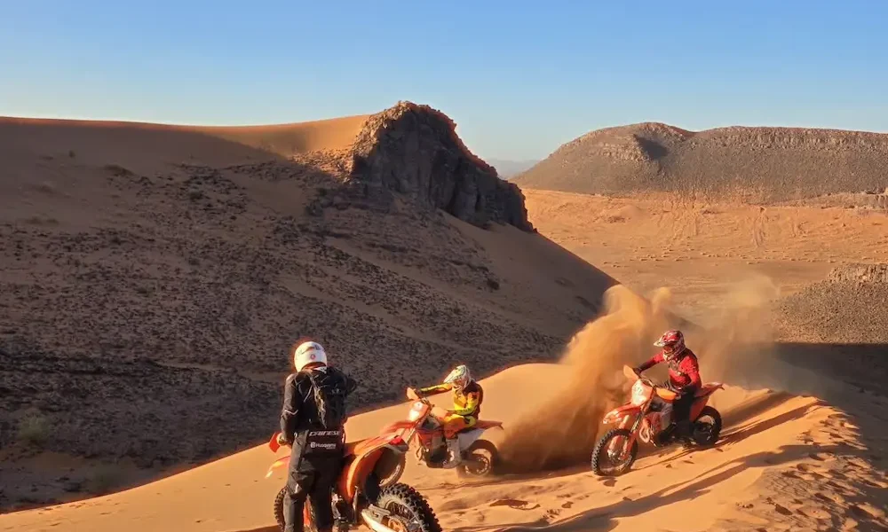 Piloto de enduro saltando una duna de arena en Marruecos